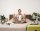 Portrait of young man meditating on a bed after packing suitcase for summer holiday, sitting with crossed legs in zen, nirvana pose, relaxing, hoping for something. Tourism and mindfulness concept